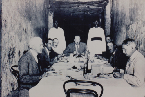 black and white photograph of James Poitrine, Harry Burton, Alfred Lucas, Arthur Callender, Arthur Mace, Howard Carter and Alan Gardiner lunching in the Valley of the Kings